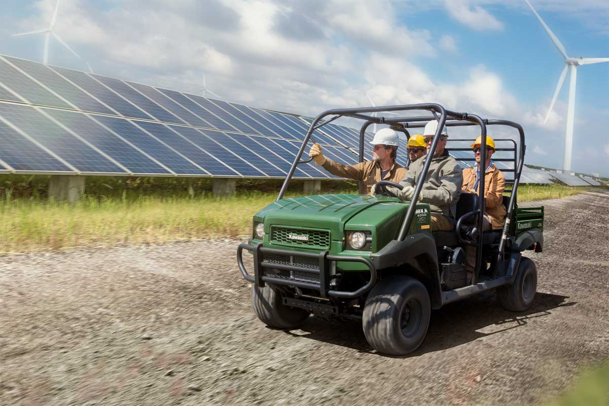 Three-quarter front angle of four people riding a side x side on a jobsite.