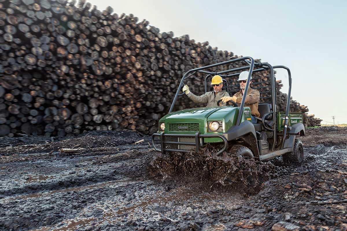 Three-quarter front angle of two people riding a side x side on a jobsite.