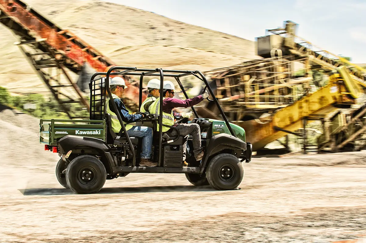 Side angle of four people driving a side x side off-road.