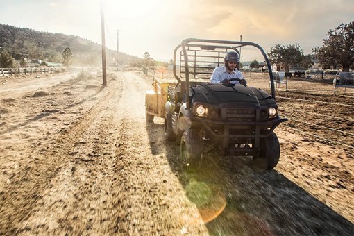 Front angle of a person driving a side x side on a ranch. opens in a new window