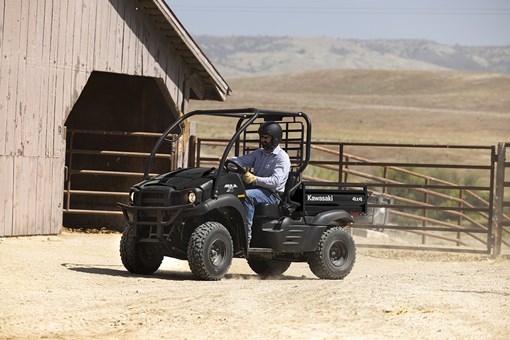 Side angle of a person driving a black side x side on a ranch. opens in a new window