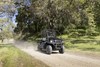 Three-quarter front angle of a person driving a black side x side on a ranch.