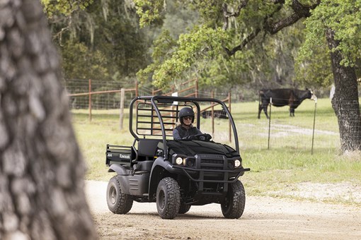 Three-quarter front angle of a person driving a side x side on a ranch. opens in a new window