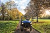 Front angle of a person driving a blue side x side on a property.