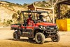 Three-quarter front angle of two people driving a side x side on a jobsite.