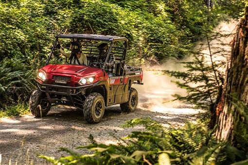 Three-quarter front angle of two people driving a side x side off-road. opens in a new window