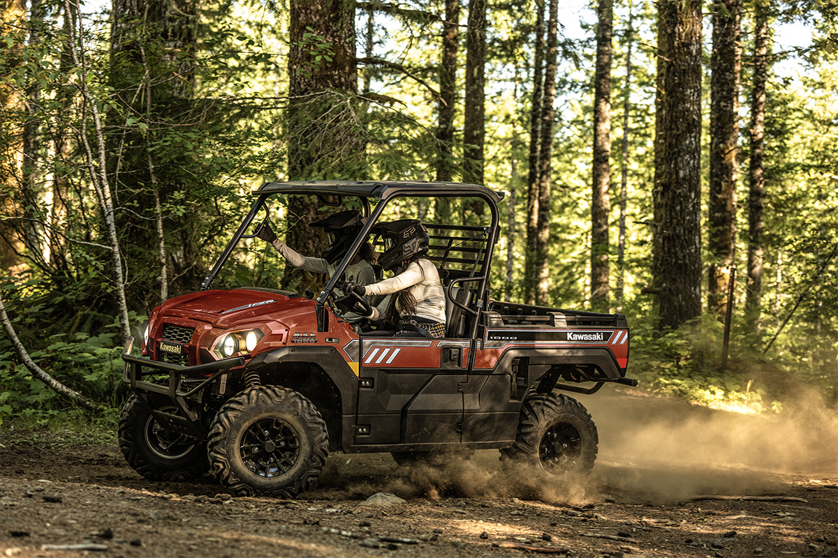 Side angle of two people driving a side x side off-road.
