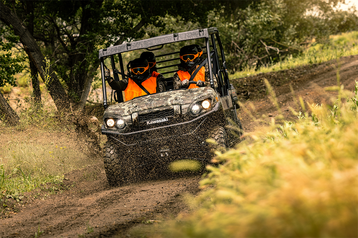 Front angle of four people driving a side x side off-road.