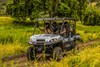 Three-quarter front angle of four people driving a side x side off-road.