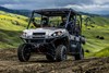 Front angle of three people driving a side x side off-road.