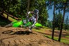 Front angle of a person riding a motorcycle over a small jump on a dirt track.