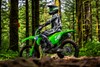 Side angle of a person seated on a motorcycle parked on an off-road course.