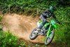 Three-quarter front angle of a person riding a motorcycle on an off-road course.
