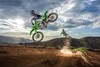 Side angle of two people riding separate motorcycles on a dirt track, whipping in midair.