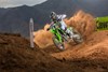Three-quarter front angle of a person riding a motorcycle around a bend on a dirt track.