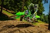 Front angle of a person riding a motorcycle, scrubbing over a small hill on a dirt track.