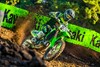 Three-quarter front angle of a person riding a motorcycle around a bend on a dirt track.
