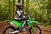 Side angle of a person seated on a motorcycle parked on an off-road course.