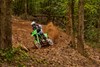 Three-quarter front angle of a person riding a motorcycle on an off-road course.