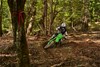 Front angle of a person riding a motorcycle around a bend on an off-road course.
