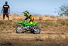 Side angle of a person riding a motorcycle off-road under adult supervision.