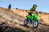 Three-quarter front angle of a person riding a motorcycle off-road under adult supervision.