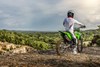 Three-quarter rear angle of a person seated on a motorcycle off-road.