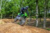 Three-quarter front angle of a person riding a motorcycle on an off-road course.
