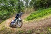 Three-quarter front angle of a person riding a motorcycle around a bend on an off-road course.