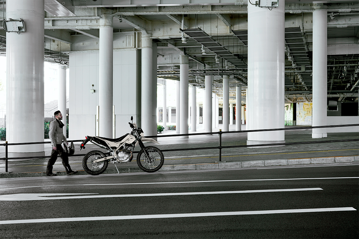 Side angle of a motorcycle parked on the shoulder of a road.