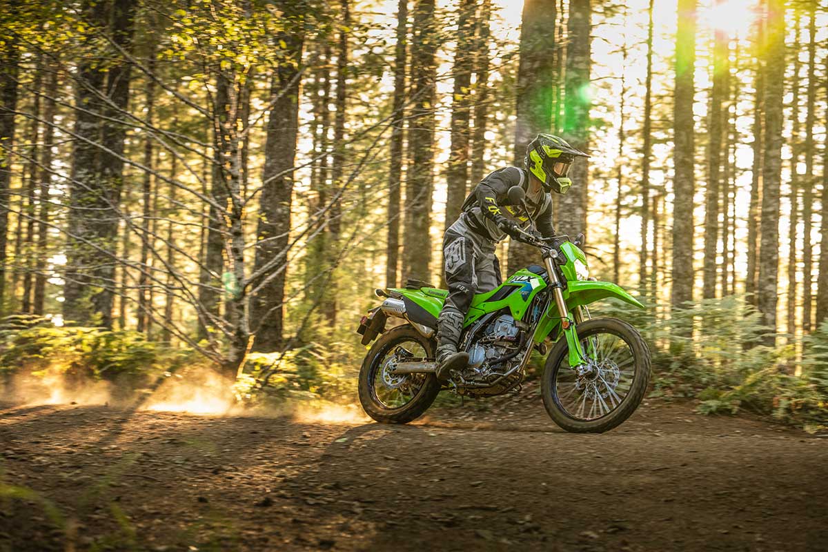 Side angle of a person riding a green motorcycle off-road.