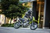 Side angle of a person riding a motorcycle on a city street.