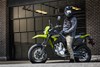 Side angle of a person seated on a motorcycle on pavement.