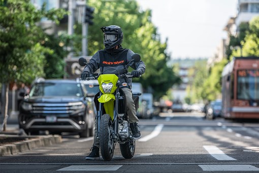 Front angle of a person riding a motorcycle paused at a traffic light. opens in a new window