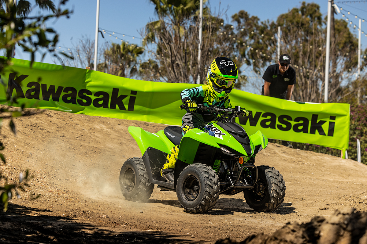 Three-quarter front angle of a person riding an ATV on a closed course under adult supervision.