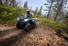 Three-quarter front angle of a person riding an ATV off-road.
