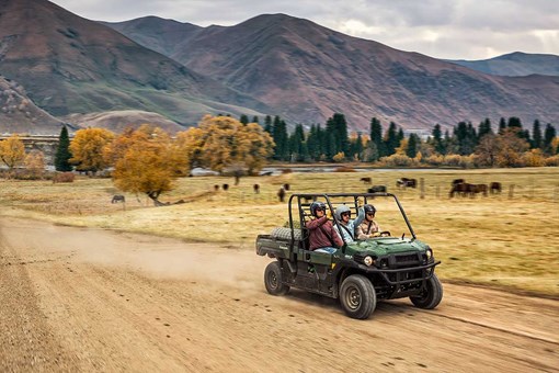 Three-quarter front angle of three people riding in a side x side at a ranch. opens in a new window