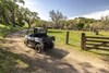 Three-quarter rear angle of a person driving a side x side on a ranch.