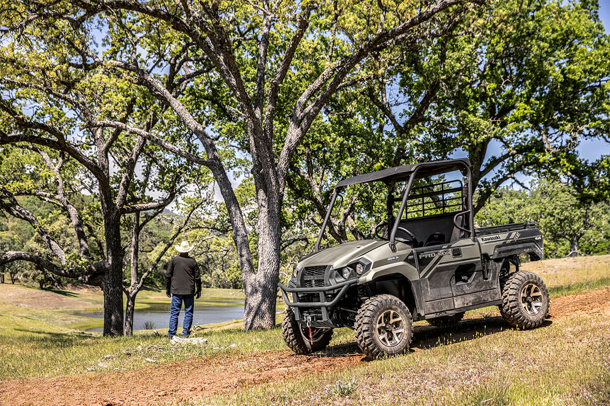 Three-quarter front angle of a person standing next to a parked side x side off-road.