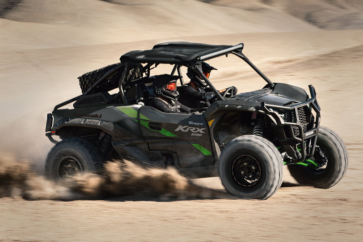 Side angle of two people driving a black side x side off-road.