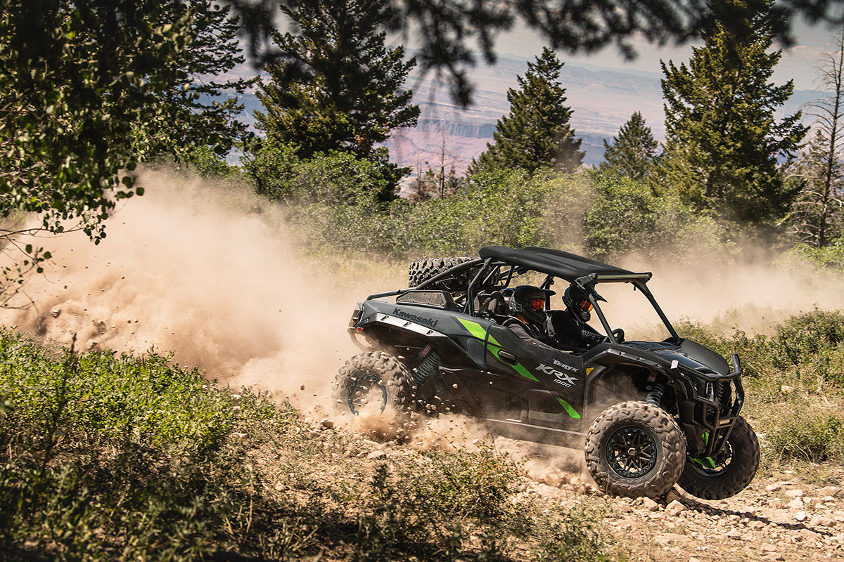 Side angle of two people driving a side x side off-road.