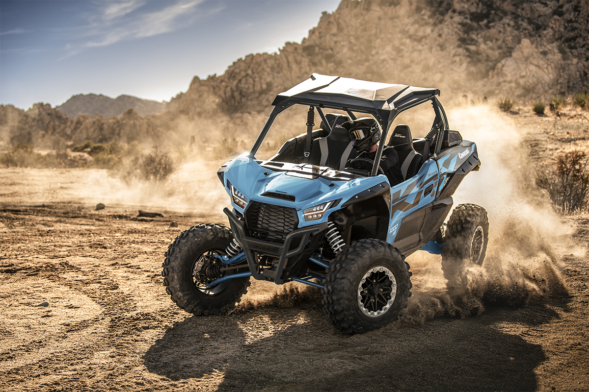 Three-quarter front angle of a person riding a blue side x side off-road.