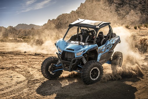 Three-quarter front angle of a person riding a blue side x side off-road. opens in a new window