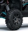 Close-up view of the front left tire of a side x side staged in a white studio background.