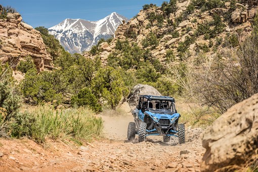 Front angle of four people driving a side x side off-road. opens in a new window