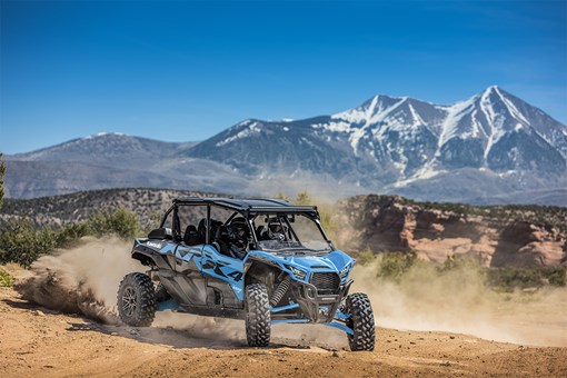 Three-quarter front angle of three people driving a side x side off-road. opens in a new window