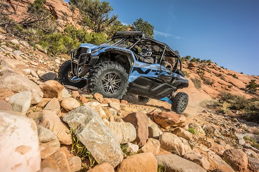 Side angle of three people driving a side x side off-road. opens in a new window