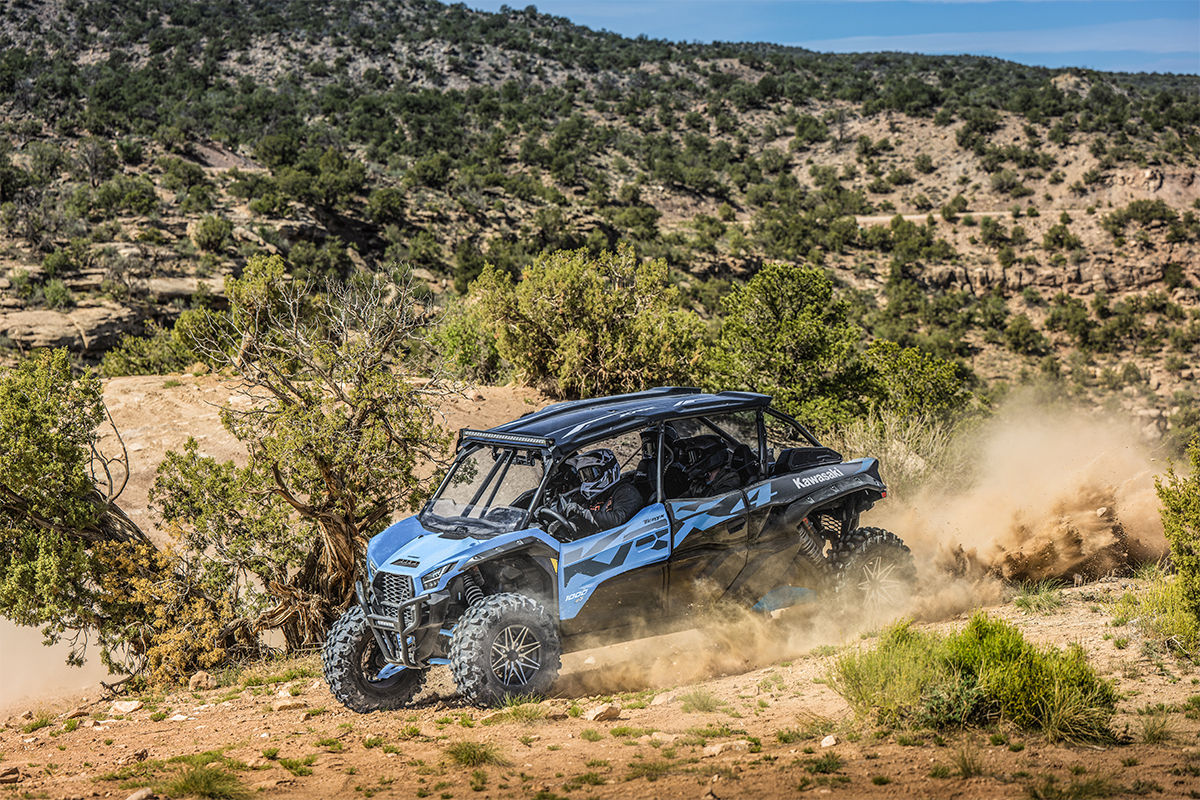 Side angle of four people driving a side x side off-road.