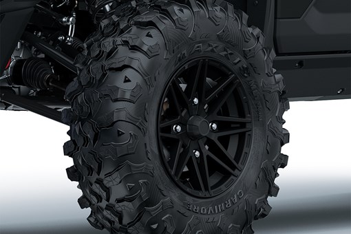 Close-up view of the front-left tire of a side x side staged in a white studio background. opens in a new window