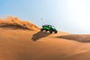 Side angle of a person driving a side x side off-road on top of a dune.